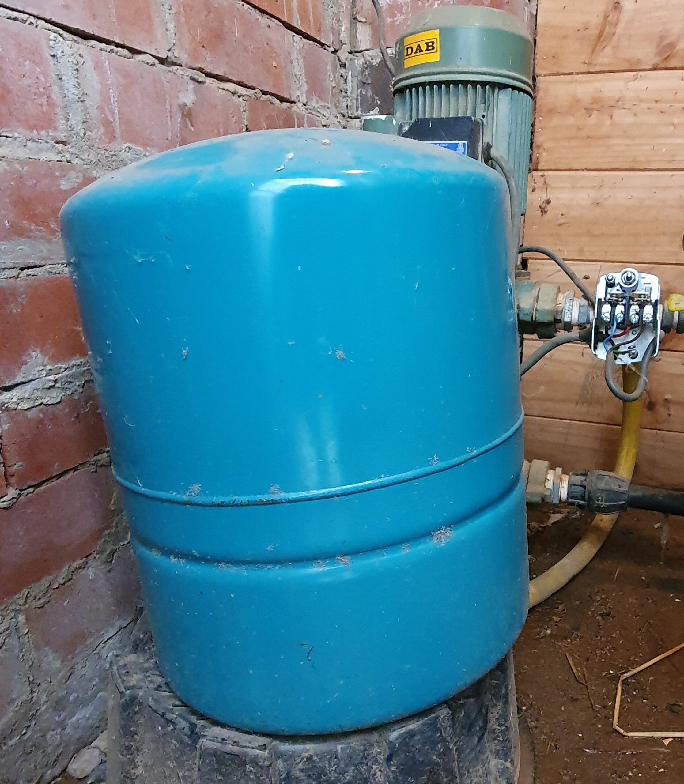 Photograph of a real pressure tank, surface pump and pressure switch on a rainwater supply system