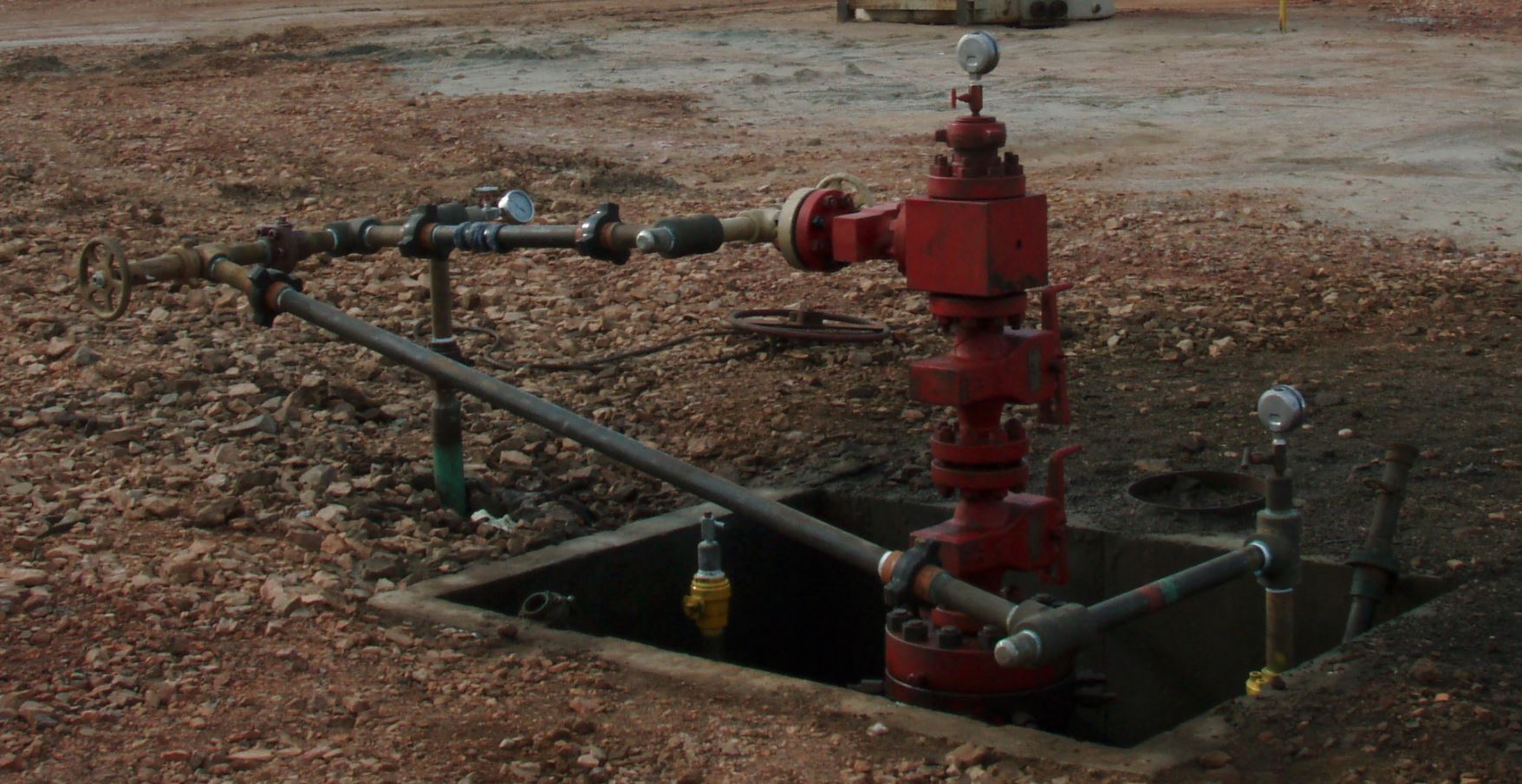 Photograph of a real outdoor wellhead showing several plumbing pressure gauges